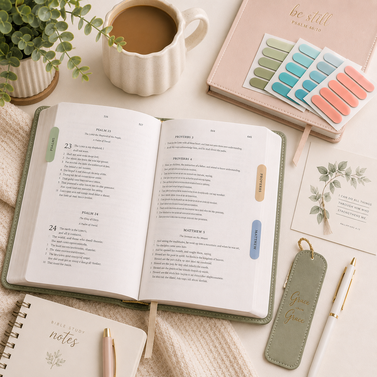 Open book with a cup of coffee, planner, and stationery on a light surface with sticky page tabs for journalling and bible study.